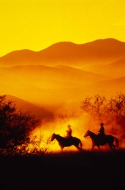 Two Cowboys on Horseback at Sunset